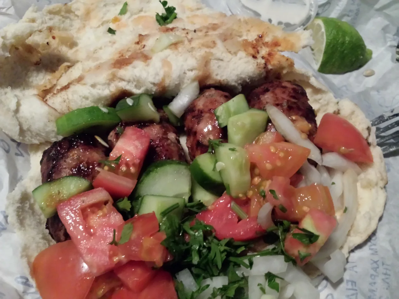 Sheftalia served in pita with vegetables.