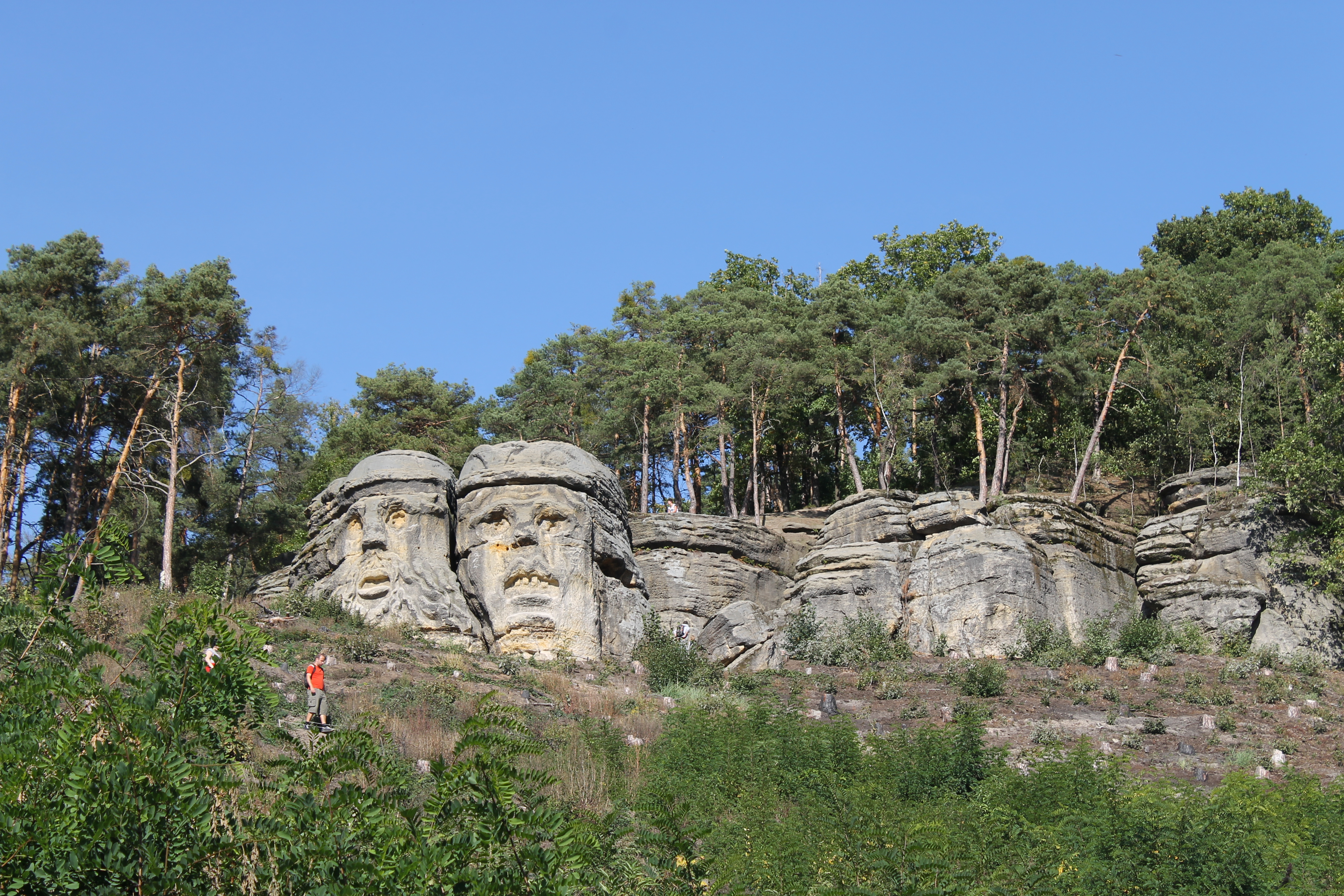 Two giant devil head sculptures carved into sandstone cliff near Zelizy